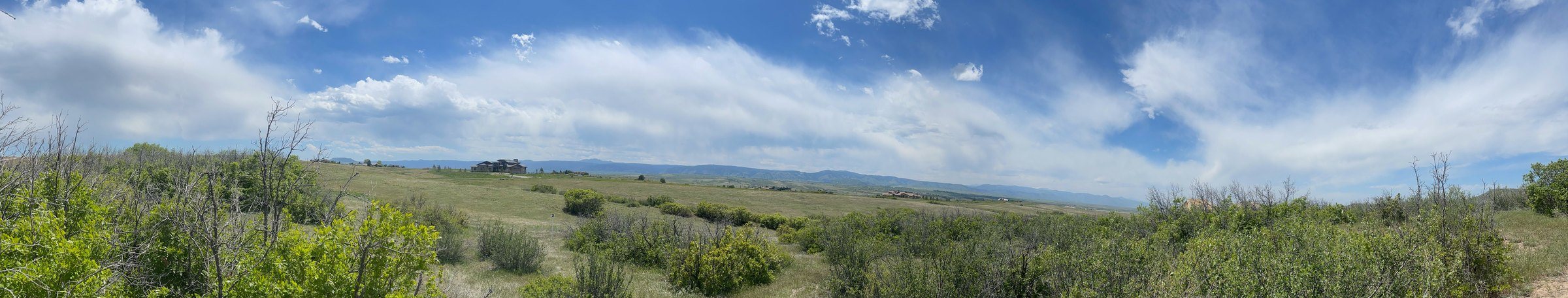 Panoramic photograph taken from Lot 21, looking west across open meadow to the mountains on the horizon.